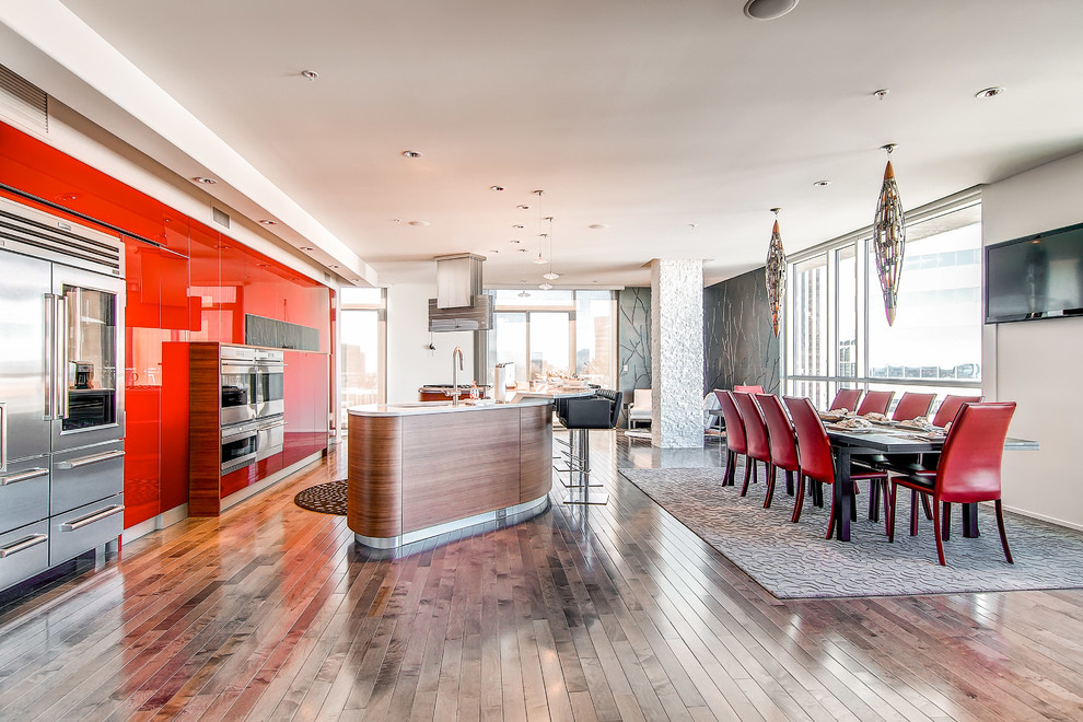 Imagen de cocina contemporánea abierta con armarios con paneles lisos, puertas de armario rojas y electrodomésticos de acero inoxidable