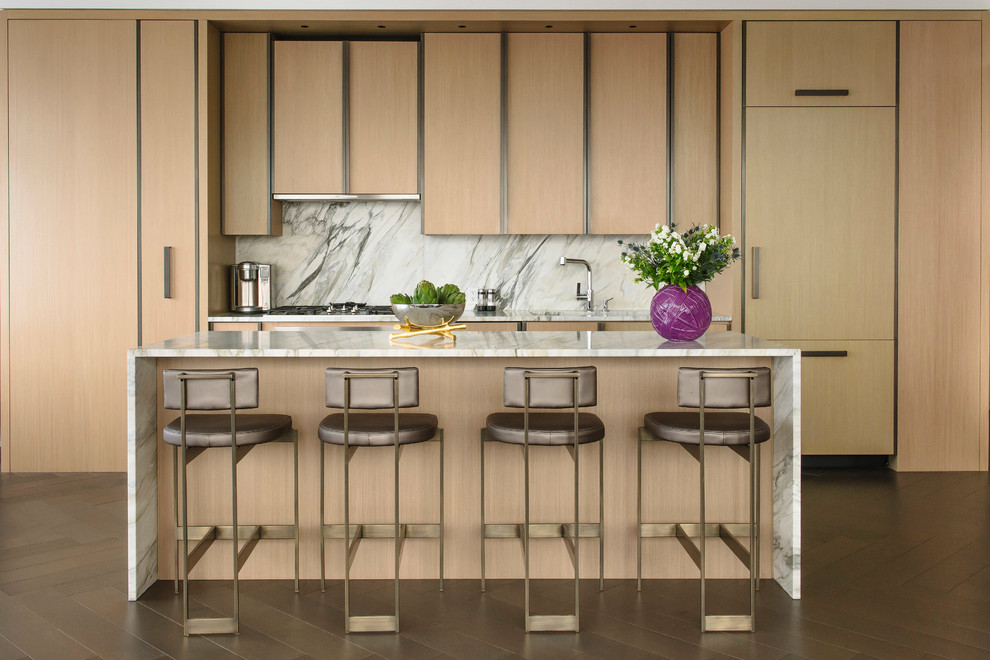 ニューヨークにあるコンテンポラリースタイルのおしゃれなアイランドキッチン (フラットパネル扉のキャビネット、淡色木目調キャビネット、石スラブのキッチンパネル、パネルと同色の調理設備、茶色い床) の写真