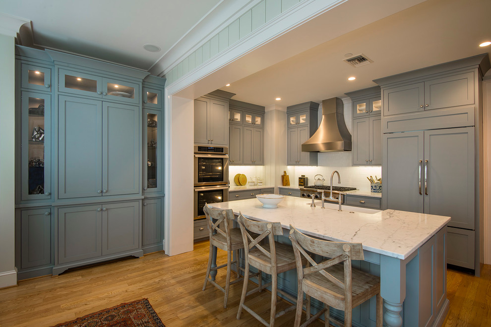 Example of a small transitional l-shaped medium tone wood floor enclosed kitchen design in Charleston with a farmhouse sink, beaded inset cabinets, green cabinets, marble countertops, white backsplash, stainless steel appliances and an island