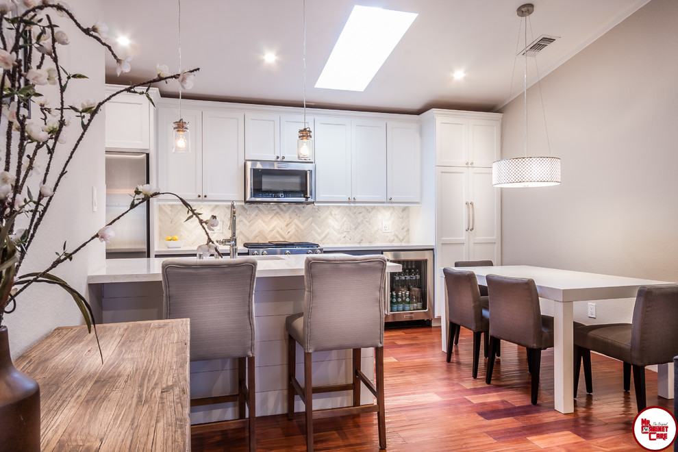 Inspiration for a small contemporary galley medium tone wood floor eat-in kitchen remodel in Orange County with an undermount sink, raised-panel cabinets, white cabinets, quartz countertops, white backsplash, stainless steel appliances and no island