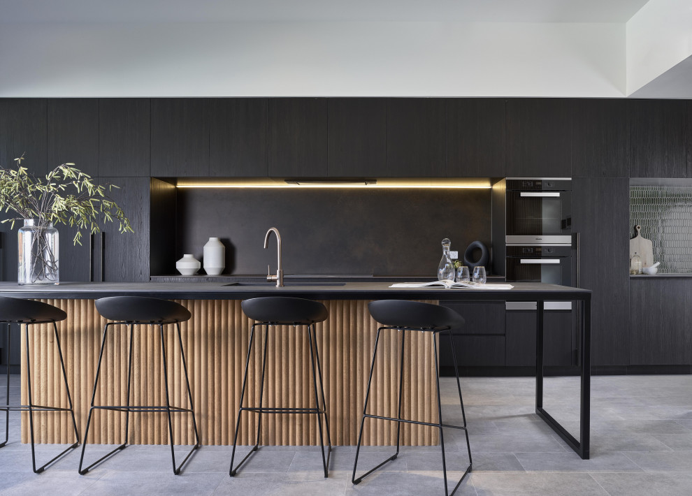 Modern galley kitchen in Brisbane with a submerged sink, flat-panel cabinets, black cabinets, black splashback, stainless steel appliances, an island and grey floors.