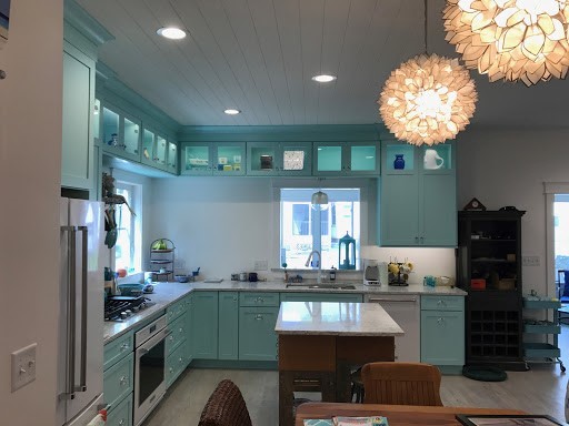 Modern inredning av ett mellanstort kök, med en undermonterad diskho, skåp i shakerstil, blå skåp, marmorbänkskiva, vita vitvaror, ljust trägolv, en köksö och beiget golv