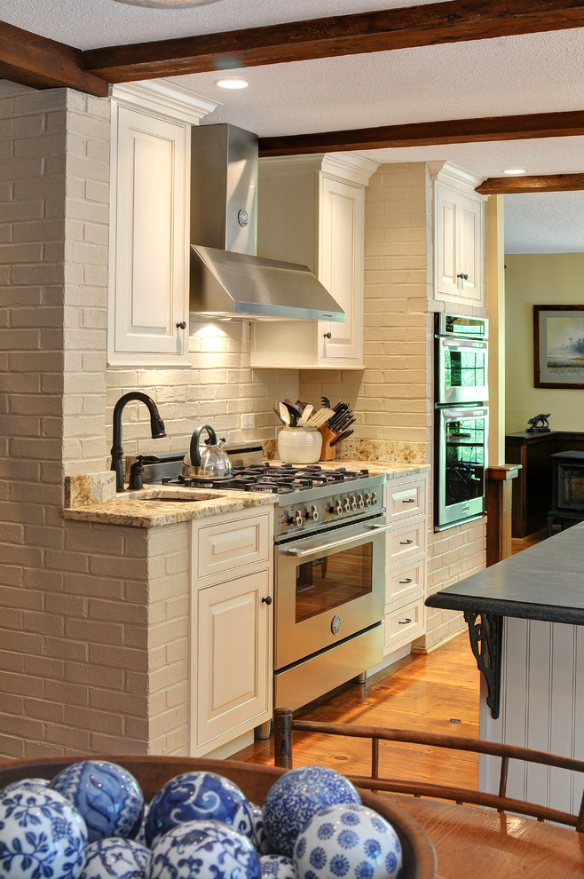 Inspiration för ett mellanstort vintage kök, med vita skåp, granitbänkskiva, rostfria vitvaror, en köksö, en rustik diskho, luckor med upphöjd panel, mellanmörkt trägolv och brunt golv