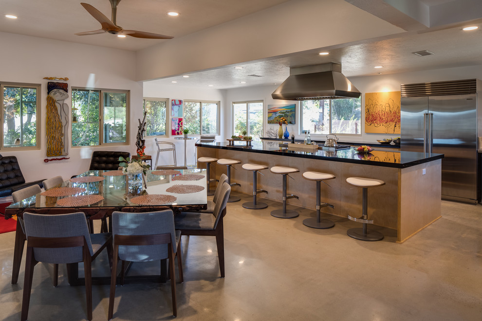 This is an example of a large modern l-shaped open plan kitchen in San Diego with open cabinets, light wood cabinets, composite countertops, stainless steel appliances, concrete flooring and an island.