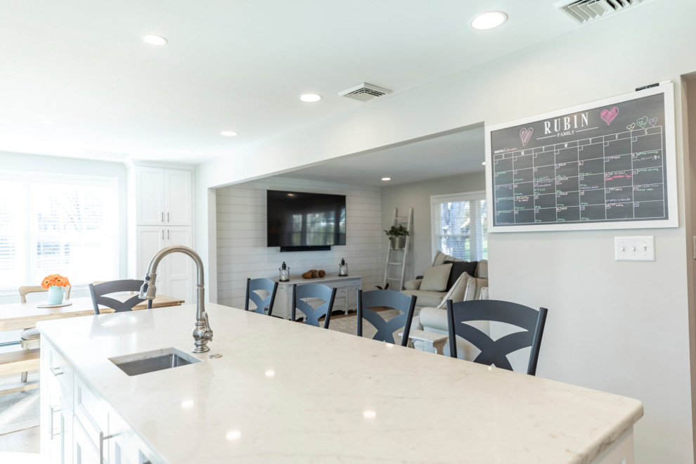 Medium sized traditional l-shaped open plan kitchen in Philadelphia with a submerged sink, recessed-panel cabinets, white cabinets, quartz worktops, white splashback, porcelain splashback, stainless steel appliances, medium hardwood flooring, an island, brown floors and beige worktops.