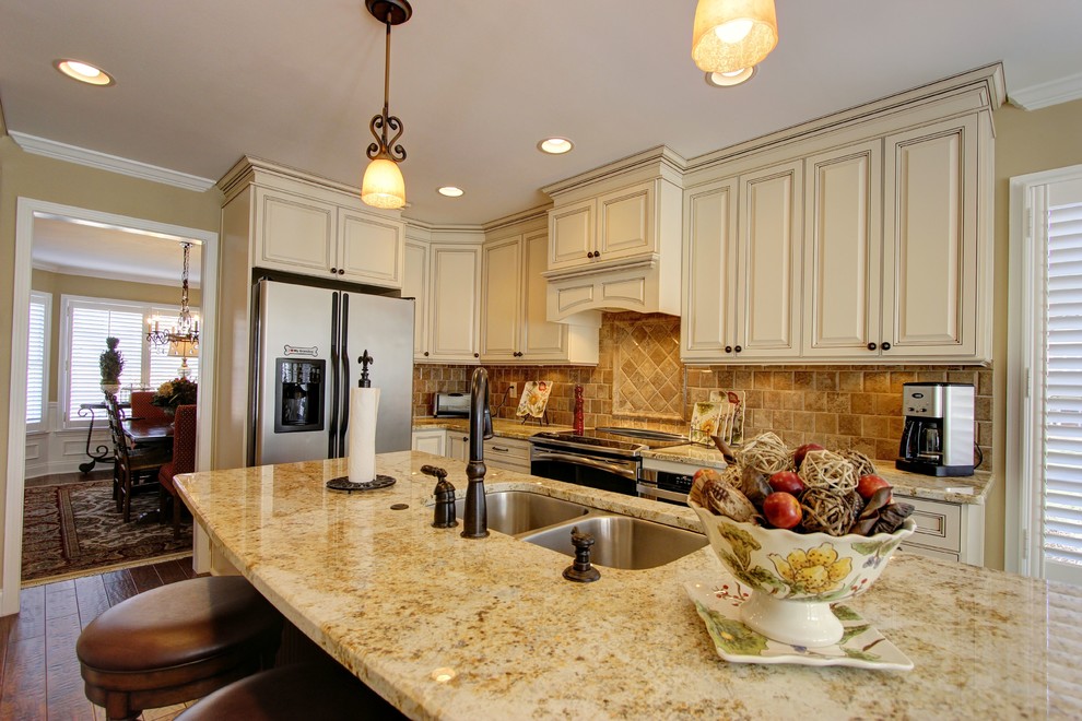 Exempel på ett stort klassiskt kök, med en dubbel diskho, luckor med upphöjd panel, beige skåp, granitbänkskiva, brunt stänkskydd, stänkskydd i stenkakel, mellanmörkt trägolv och en köksö
