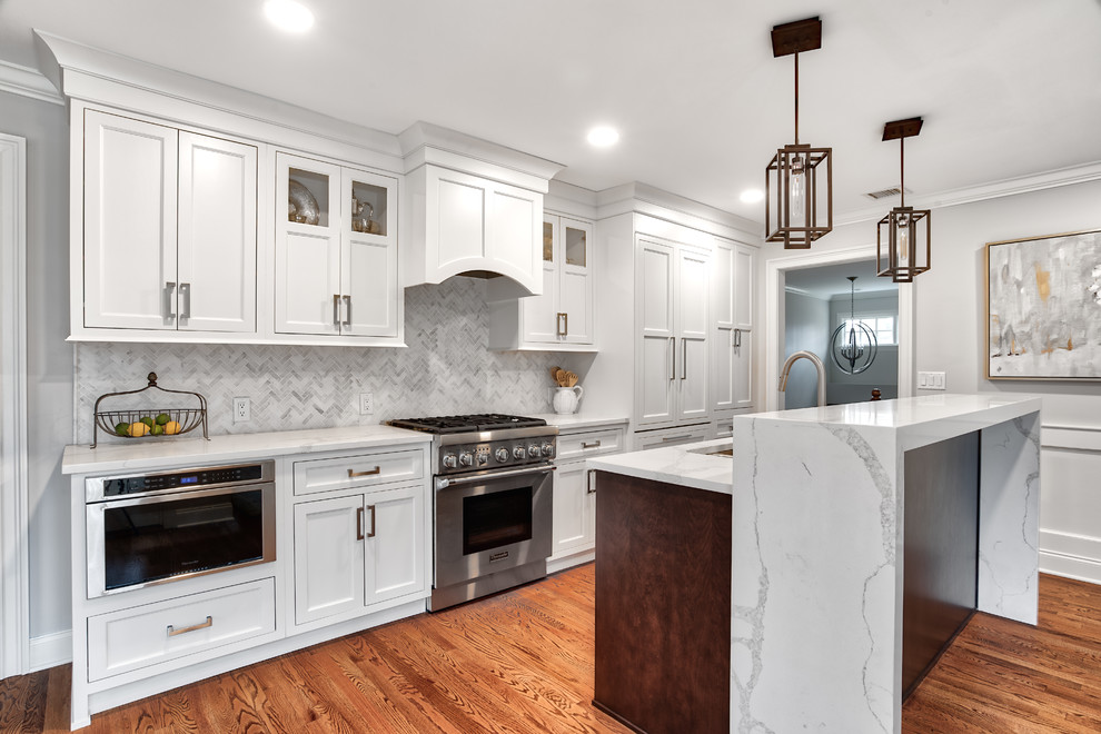 Example of a mid-sized transitional galley medium tone wood floor and brown floor eat-in kitchen design in New York with an undermount sink, white cabinets, quartzite countertops, white backsplash, mosaic tile backsplash, stainless steel appliances, an island, white countertops and shaker cabinets