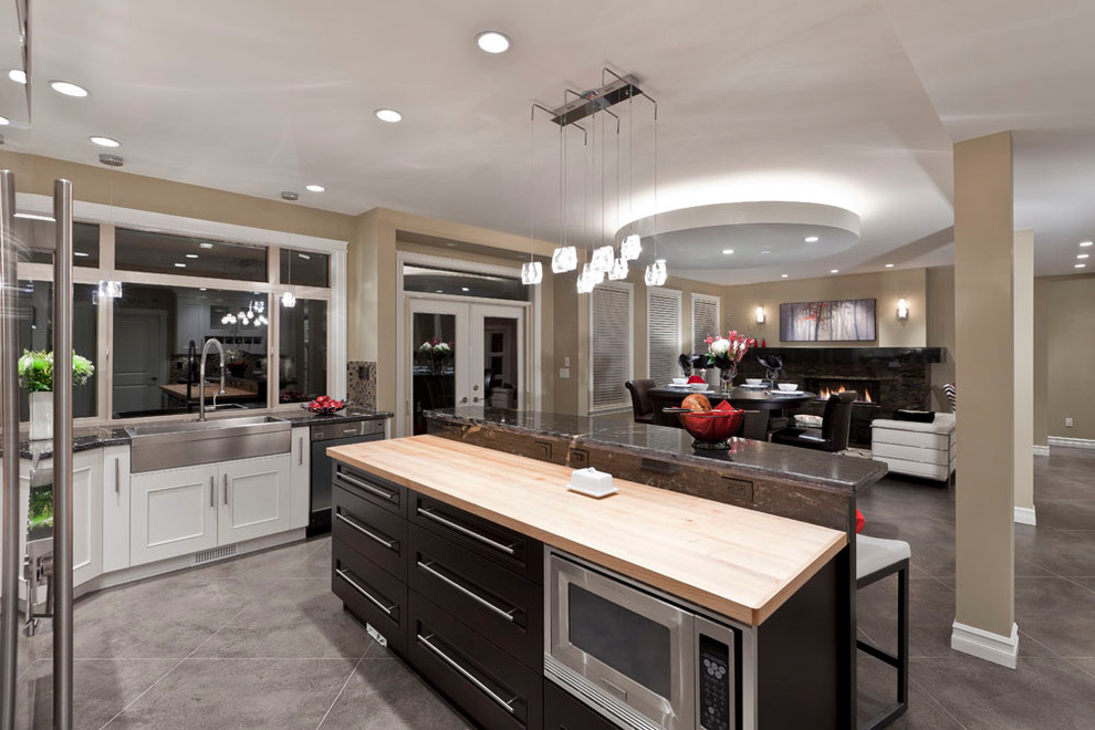 Example of a large trendy u-shaped open concept kitchen design in Vancouver with wood countertops, a farmhouse sink, recessed-panel cabinets, white cabinets, multicolored backsplash and stainless steel appliances