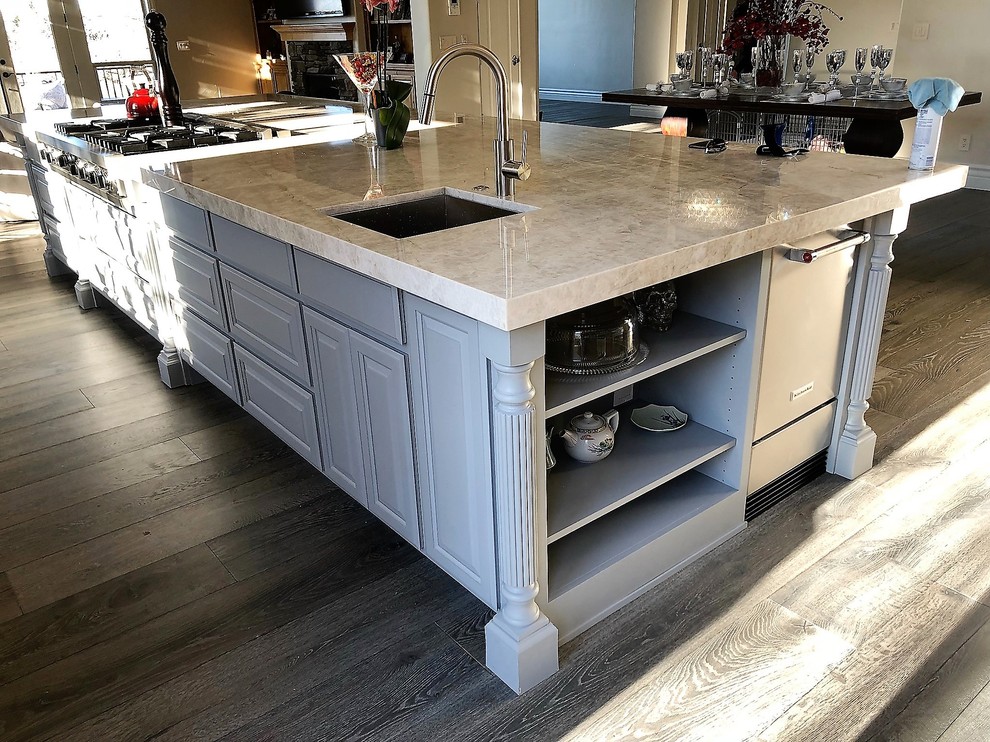Photo of a large mediterranean l-shaped kitchen/diner in Sacramento with a submerged sink, raised-panel cabinets, grey cabinets, marble worktops, grey splashback, marble splashback, stainless steel appliances, medium hardwood flooring, an island and grey floors.