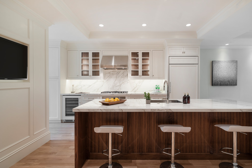 Inspiration for a light wood floor and tray ceiling eat-in kitchen remodel in Boston with an undermount sink, recessed-panel cabinets, white cabinets, solid surface countertops, gray backsplash, stainless steel appliances, an island and gray countertops