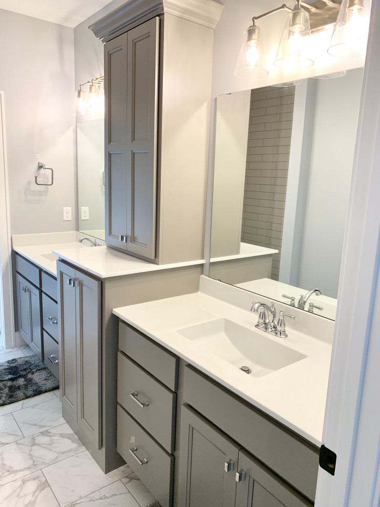 Große Klassische Wohnküche in L-Form mit Landhausspüle, flächenbündigen Schrankfronten, weißen Schränken, Quarzwerkstein-Arbeitsplatte, Küchenrückwand in Weiß, Rückwand aus Metrofliesen, Küchengeräten aus Edelstahl, braunem Holzboden, Kücheninsel, braunem Boden und grauer Arbeitsplatte in Sonstige