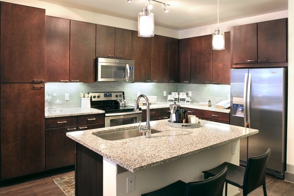Klassisk inredning av ett mellanstort flerfärgad flerfärgat kök, med en undermonterad diskho, släta luckor, skåp i mörkt trä, granitbänkskiva, blått stänkskydd, stänkskydd i stickkakel, rostfria vitvaror, vinylgolv, en köksö och brunt golv