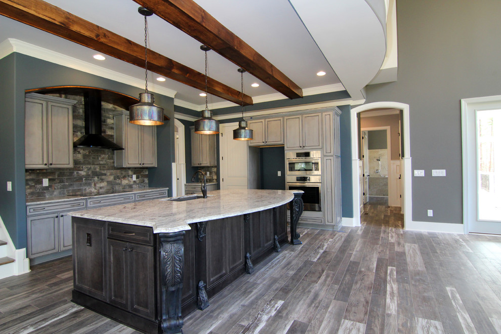 Example of a huge classic l-shaped ceramic tile open concept kitchen design in Raleigh with a single-bowl sink, recessed-panel cabinets, gray cabinets, granite countertops, gray backsplash, ceramic backsplash, stainless steel appliances and an island