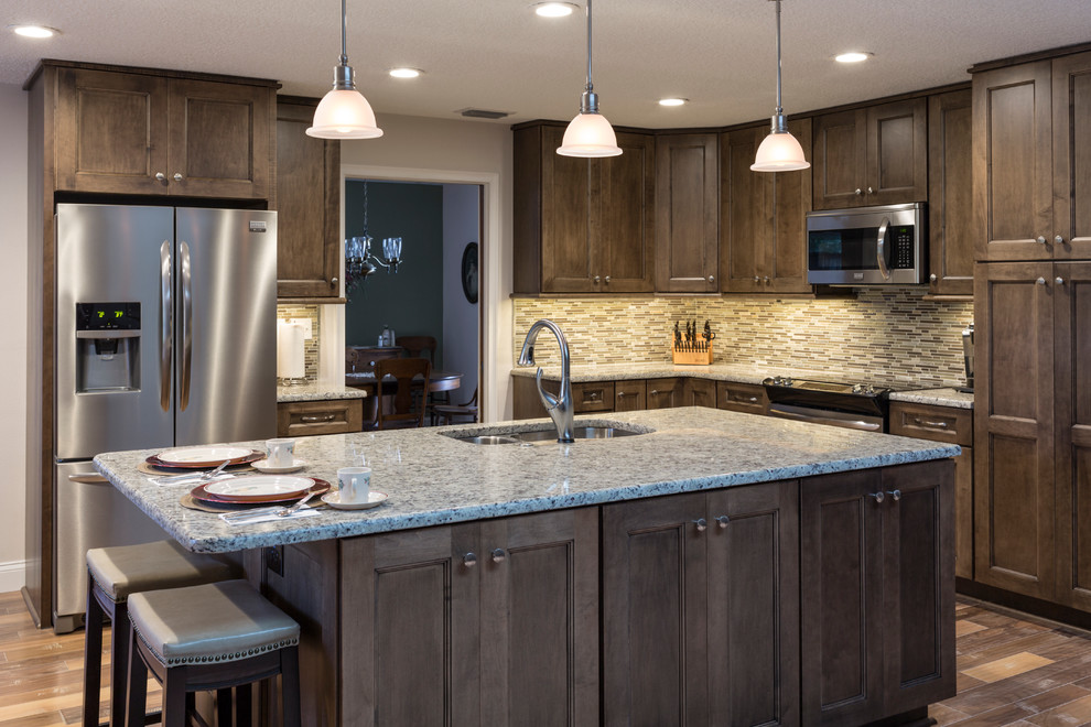 Example of a small trendy l-shaped light wood floor open concept kitchen design in Tampa with an undermount sink, shaker cabinets, dark wood cabinets, granite countertops, multicolored backsplash, porcelain backsplash, stainless steel appliances and an island