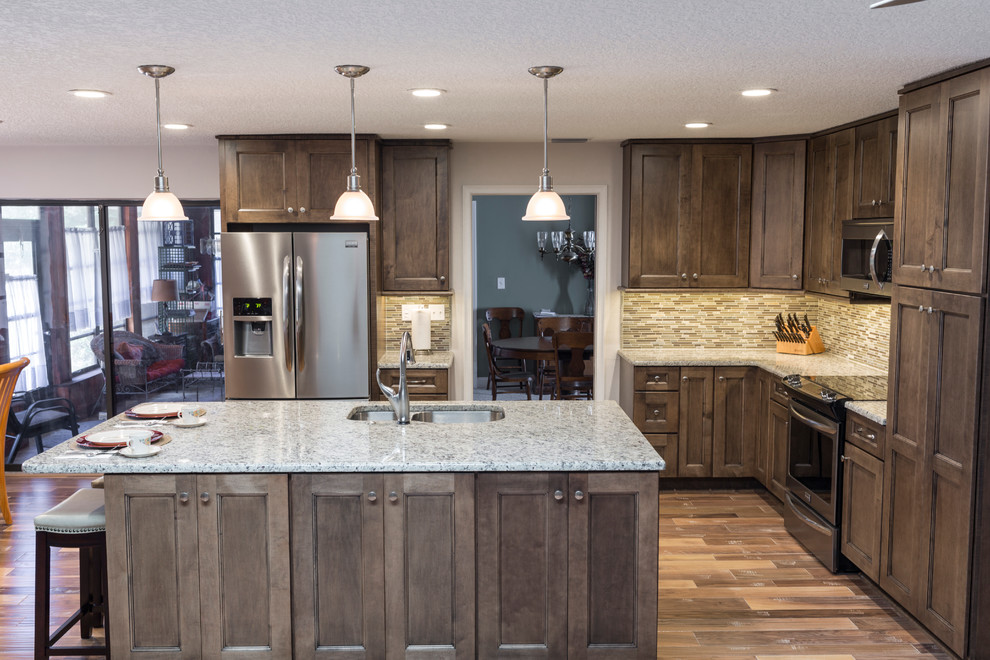 Small trendy l-shaped light wood floor open concept kitchen photo in Tampa with an undermount sink, shaker cabinets, dark wood cabinets, granite countertops, multicolored backsplash, porcelain backsplash, stainless steel appliances and an island
