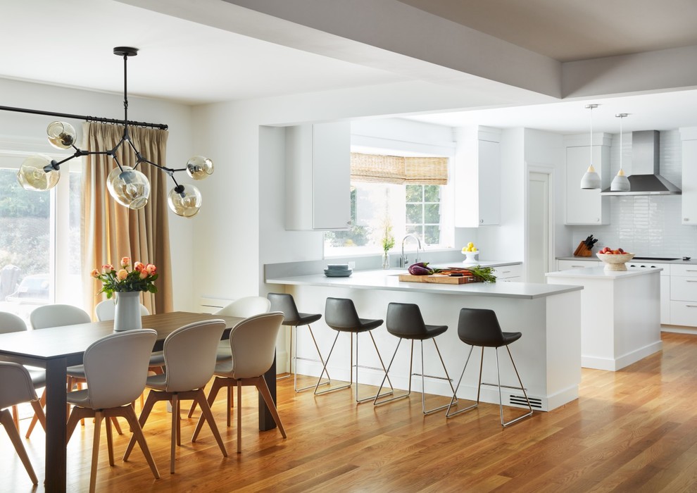 Large contemporary u-shaped kitchen/diner in New York with flat-panel cabinets, white cabinets, engineered stone countertops, white splashback, an island, grey worktops and medium hardwood flooring.