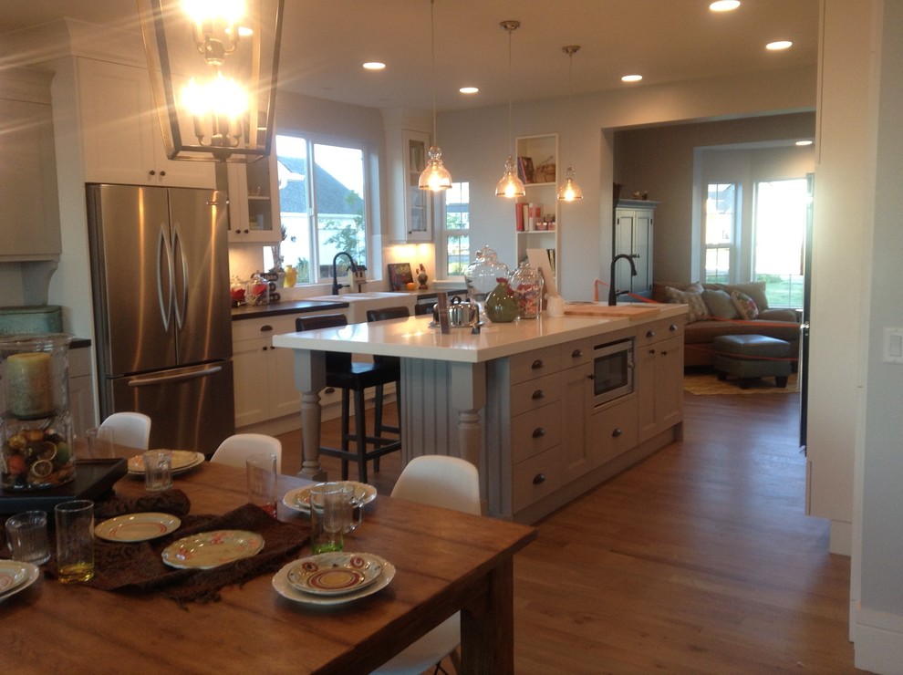 Example of a large transitional galley light wood floor eat-in kitchen design in Salt Lake City with a farmhouse sink, shaker cabinets, white cabinets, quartz countertops, white backsplash, subway tile backsplash, stainless steel appliances and an island