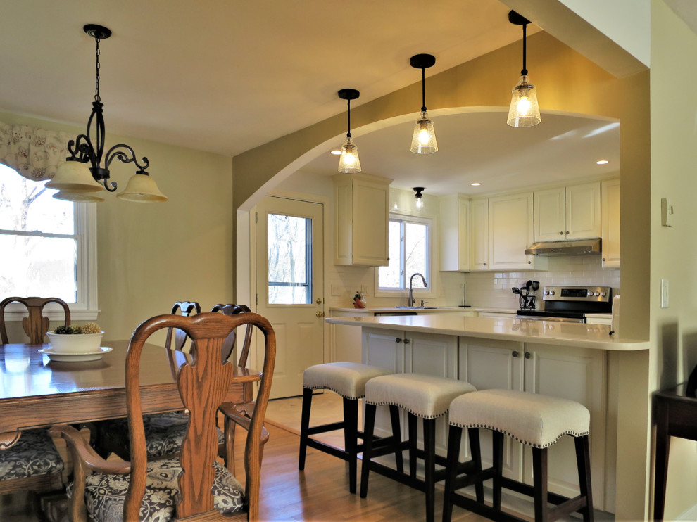 Idéer för att renovera ett litet vintage kök, med en undermonterad diskho, luckor med upphöjd panel, gula skåp, bänkskiva i kvarts, vitt stänkskydd, stänkskydd i tunnelbanekakel, rostfria vitvaror, klinkergolv i porslin, en halv köksö och flerfärgat golv