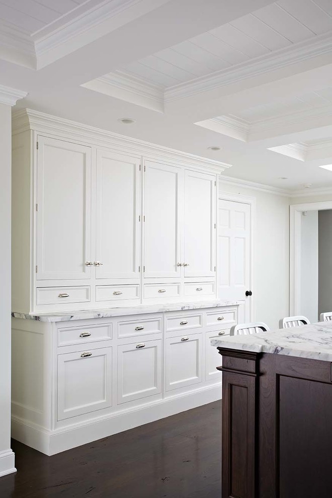 Idées déco pour une cuisine américaine classique avec un placard à porte affleurante et des portes de placard blanches.