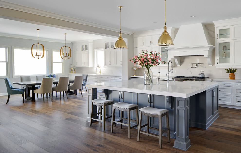 Inspiration for a mid-sized transitional galley medium tone wood floor and multicolored floor eat-in kitchen remodel in Los Angeles with white cabinets, solid surface countertops, white backsplash, marble backsplash, stainless steel appliances, an island, white countertops and recessed-panel cabinets