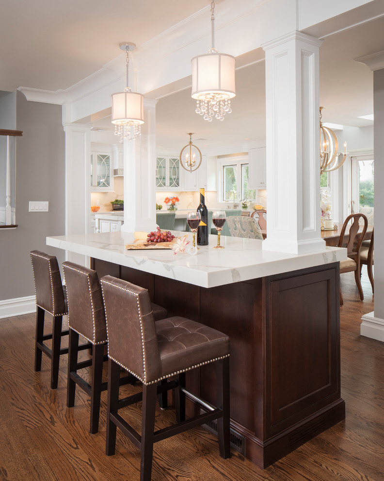 Eat-in kitchen - large transitional l-shaped medium tone wood floor and brown floor eat-in kitchen idea in New York with an undermount sink, shaker cabinets, dark wood cabinets, quartz countertops, white backsplash, subway tile backsplash, stainless steel appliances and two islands