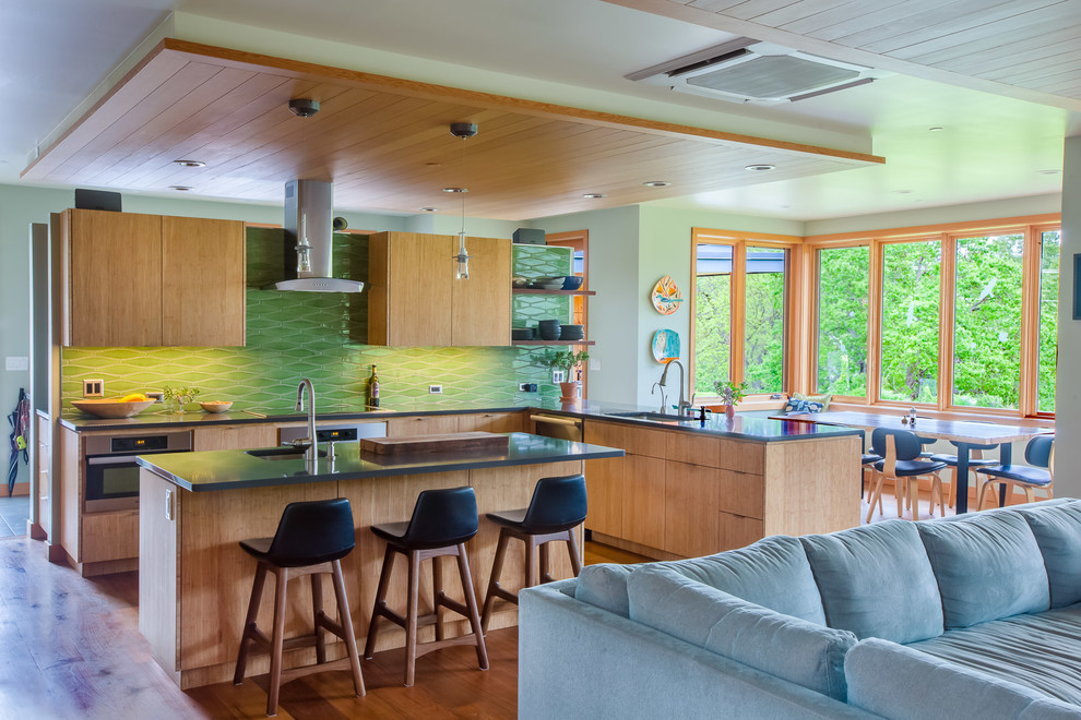 Large minimalist l-shaped medium tone wood floor open concept kitchen photo in Other with stainless steel appliances, an island, flat-panel cabinets, medium tone wood cabinets, green backsplash and an undermount sink
