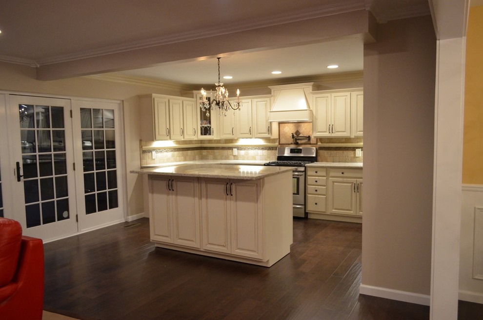 Exempel på ett stort klassiskt flerfärgad linjärt flerfärgat kök och matrum, med en enkel diskho, luckor med upphöjd panel, vita skåp, granitbänkskiva, beige stänkskydd, stänkskydd i kalk, rostfria vitvaror, mörkt trägolv, en köksö och brunt golv
