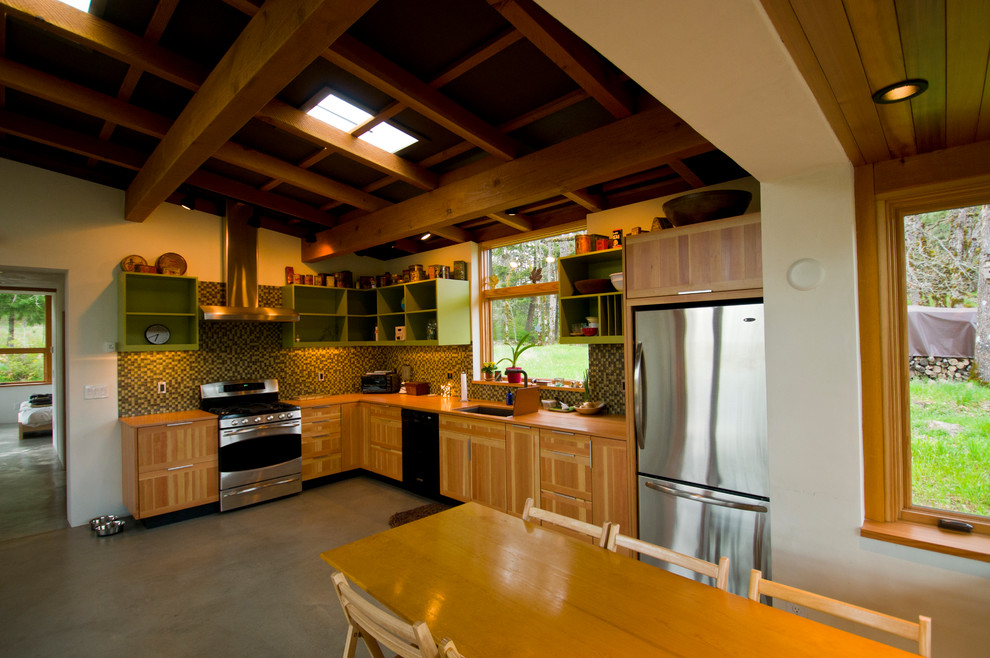 Small trendy u-shaped concrete floor eat-in kitchen photo in Other with a drop-in sink, medium tone wood cabinets, green backsplash, glass tile backsplash, stainless steel appliances and no island