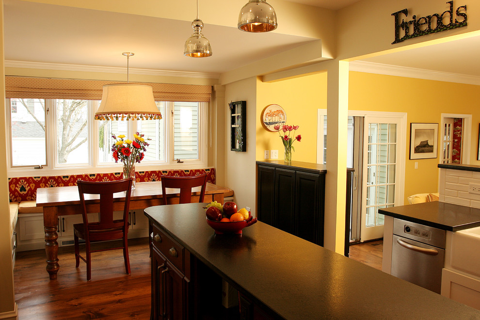 Bild på ett mellanstort lantligt kök, med en rustik diskho, luckor med infälld panel, svarta skåp, vitt stänkskydd, stänkskydd i tunnelbanekakel, rostfria vitvaror, mellanmörkt trägolv och en köksö
