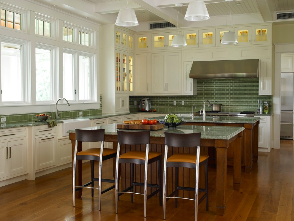 Modelo de cocinas en L tradicional con fregadero sobremueble, electrodomésticos de acero inoxidable, salpicadero gris, armarios con paneles empotrados, puertas de armario beige y encimeras verdes