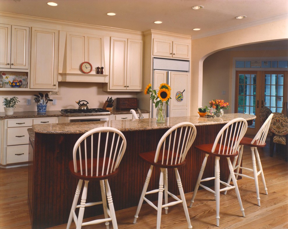 Exempel på ett stort klassiskt kök, med luckor med infälld panel, en köksö, beige skåp, granitbänkskiva, beige stänkskydd, integrerade vitvaror och ljust trägolv