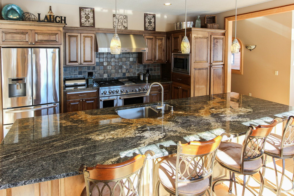 Example of a large trendy single-wall medium tone wood floor open concept kitchen design in Other with an undermount sink, raised-panel cabinets, dark wood cabinets, granite countertops, black backsplash, stone tile backsplash, stainless steel appliances and an island