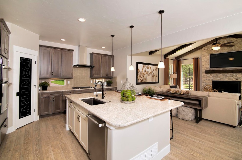 This is an example of a large classic l-shaped open plan kitchen in Denver with a submerged sink, recessed-panel cabinets, dark wood cabinets, engineered stone countertops, brown splashback, ceramic splashback, stainless steel appliances, light hardwood flooring, an island and beige floors.
