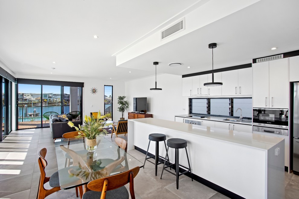 Design ideas for a large contemporary single-wall open plan kitchen in Gold Coast - Tweed with a built-in sink, flat-panel cabinets, white cabinets, marble worktops, stainless steel appliances, ceramic flooring, an island, grey floors and white worktops.