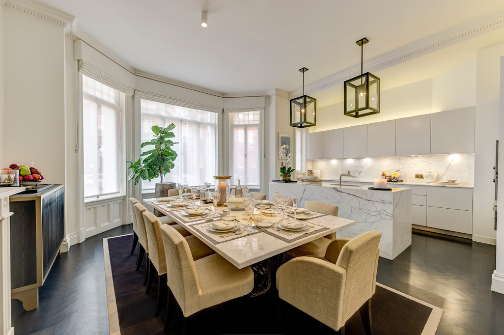 Traditional galley kitchen/diner in London with a submerged sink, glass-front cabinets, white cabinets, marble worktops, white splashback, marble splashback, dark hardwood flooring, an island, black floors and white worktops.