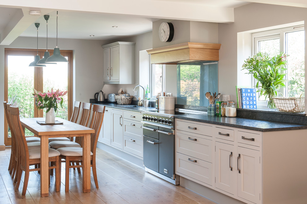 Zweizeilige, Mittelgroße Moderne Wohnküche ohne Insel mit Unterbauwaschbecken, grauen Schränken, Granit-Arbeitsplatte, Küchenrückwand in Blau, schwarzen Elektrogeräten und braunem Holzboden in Kent