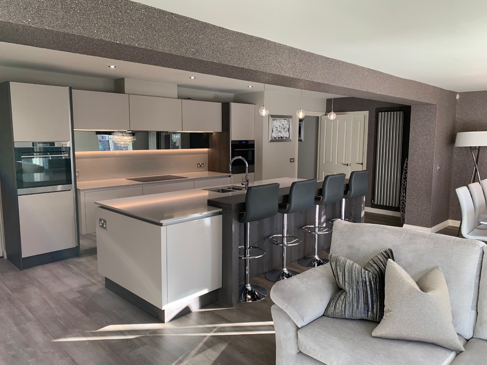 Photo of a medium sized contemporary single-wall open plan kitchen in Other with a double-bowl sink, flat-panel cabinets, black appliances, vinyl flooring and an island.