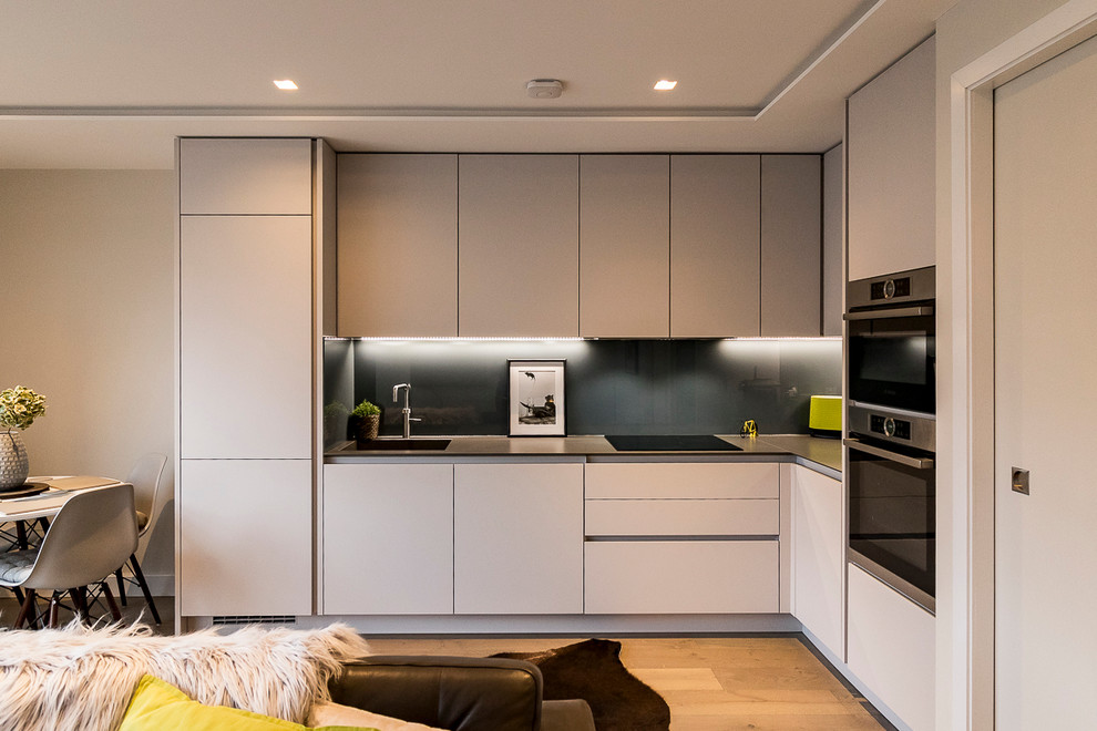 Offene, Kleine Moderne Küche mit Mineralwerkstoff-Arbeitsplatte und Elektrogeräten mit Frontblende in London