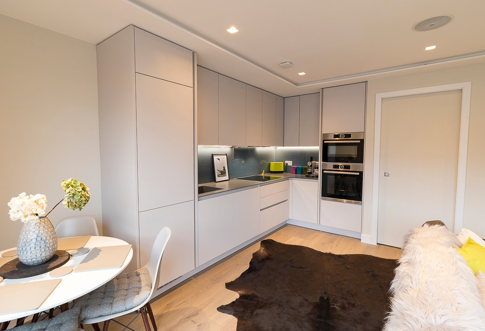 Small contemporary open plan kitchen in London with composite countertops and integrated appliances.