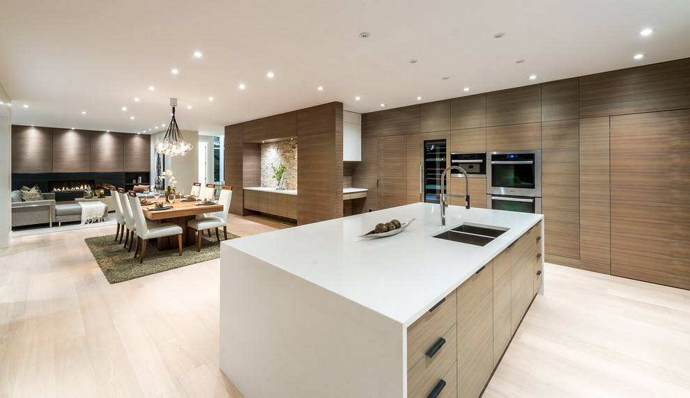 Inspiration for a large contemporary l-shaped light wood floor open concept kitchen remodel in Vancouver with an undermount sink, flat-panel cabinets, light wood cabinets, solid surface countertops, white backsplash, stone slab backsplash, stainless steel appliances and an island