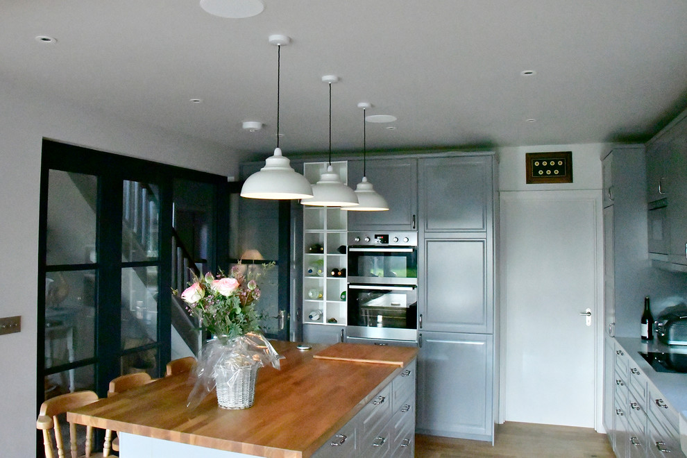Idéer för stora vintage kök, med en dubbel diskho, luckor med upphöjd panel, grå skåp, marmorbänkskiva, grått stänkskydd, stänkskydd i metallkakel, integrerade vitvaror, mellanmörkt trägolv och en köksö