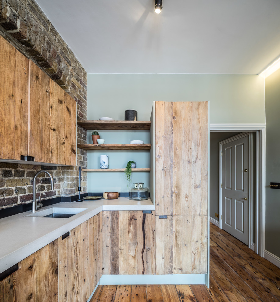 Foto på ett litet funkis kök, med släta luckor, skåp i mellenmörkt trä, bänkskiva i betong, brunt stänkskydd, stänkskydd i tegel, rostfria vitvaror och mellanmörkt trägolv