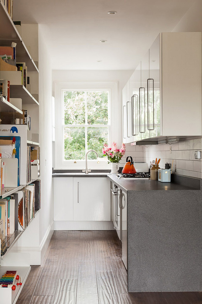 Inspiration for a small contemporary l-shaped open plan kitchen in London with flat-panel cabinets, white cabinets, laminate countertops, white splashback, ceramic splashback, stainless steel appliances, medium hardwood flooring and no island.