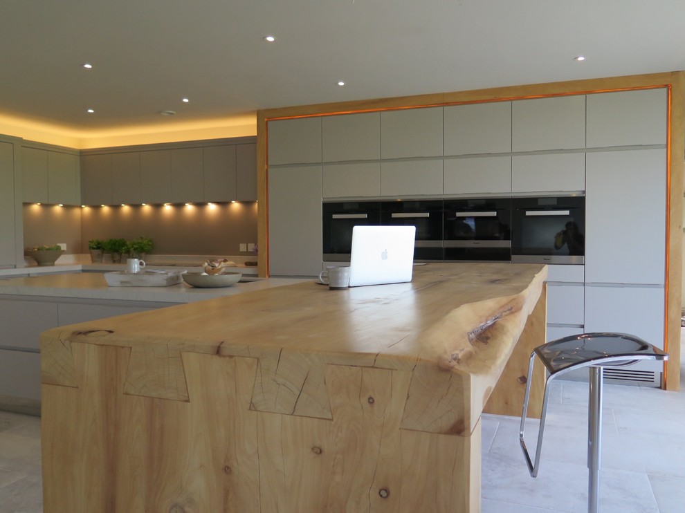 Photo of an expansive contemporary open plan kitchen in Cheshire with a double-bowl sink, flat-panel cabinets, grey cabinets, quartz worktops, grey splashback, glass sheet splashback, stainless steel appliances, porcelain flooring and multiple islands.