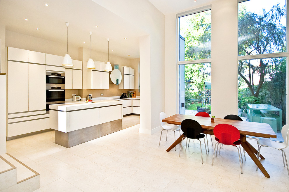 Eat-in kitchen - contemporary galley eat-in kitchen idea in London with flat-panel cabinets, white cabinets, beige backsplash, stainless steel appliances and an island