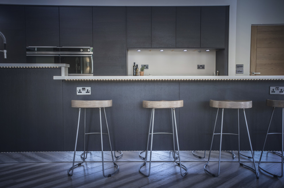 Immagine di una cucina design di medie dimensioni con ante lisce, ante in legno bruno, top in quarzite, elettrodomestici da incasso, pavimento in bambù, penisola, pavimento grigio e top bianco