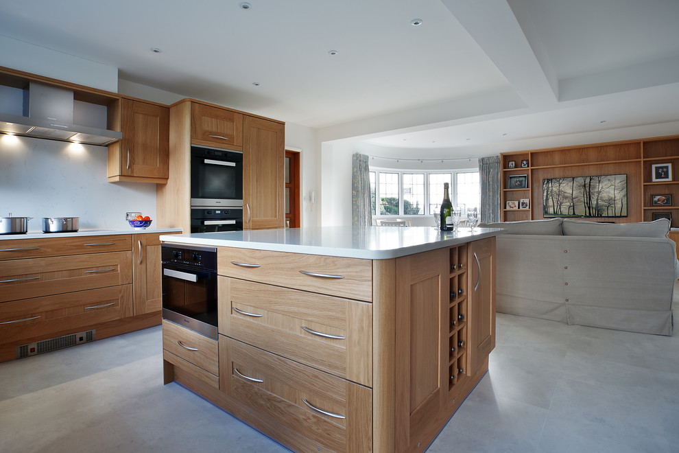 Exempel på ett stort modernt kök, med luckor med infälld panel, skåp i ljust trä, bänkskiva i kvarts, vitt stänkskydd, stänkskydd i stenkakel, rostfria vitvaror, cementgolv, en köksö och grått golv