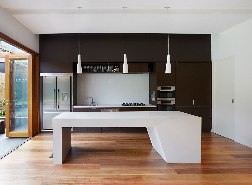 Exempel på ett mellanstort modernt linjärt kök med öppen planlösning, med en undermonterad diskho, svarta skåp, bänkskiva i kvarts, vitt stänkskydd, glaspanel som stänkskydd, rostfria vitvaror, mellanmörkt trägolv och en köksö