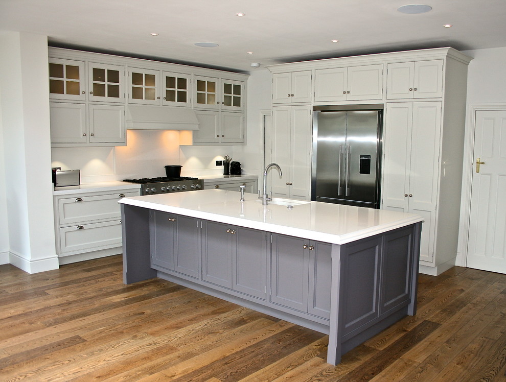Photo of a large classic l-shaped kitchen/diner in London with a submerged sink, engineered stone countertops, stainless steel appliances, dark hardwood flooring, an island, beaded cabinets, grey cabinets, white splashback and stone slab splashback.