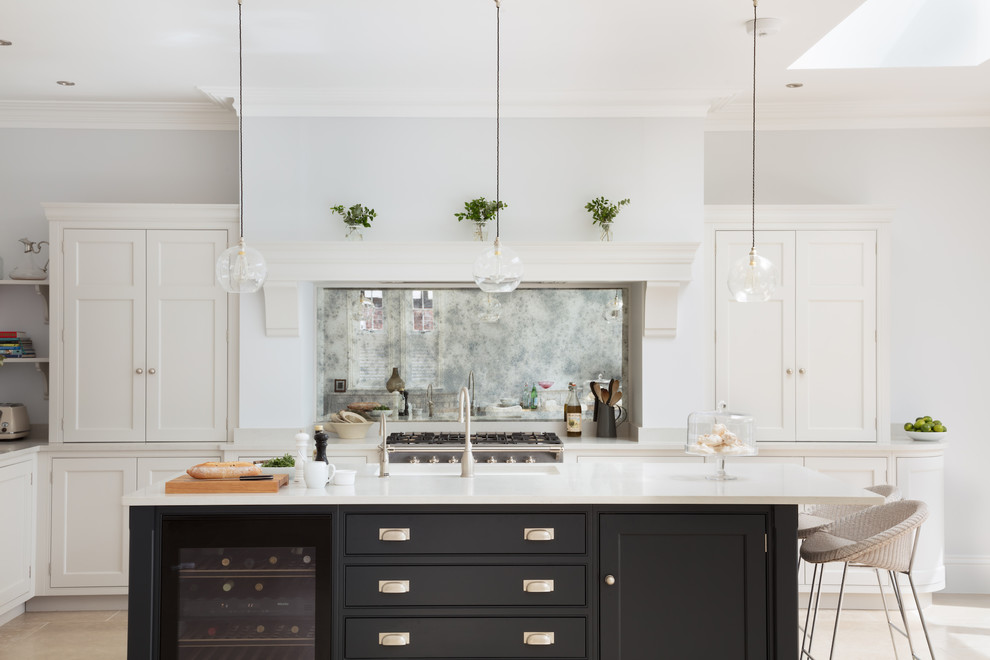 Klassisk inredning av ett mellanstort l-kök, med bänkskiva i kvartsit, stänkskydd med metallisk yta, spegel som stänkskydd, en köksö, en undermonterad diskho, skåp i shakerstil, svarta skåp och beiget golv